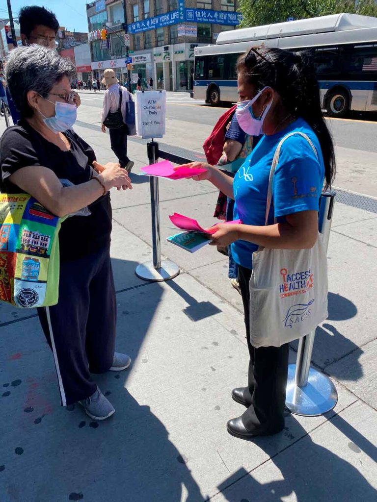 a person handing another person a flyer on the sidewalk of a New York City street